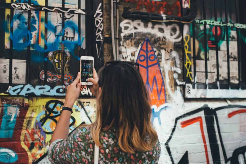 Girl takes photo of graffiti on her phone