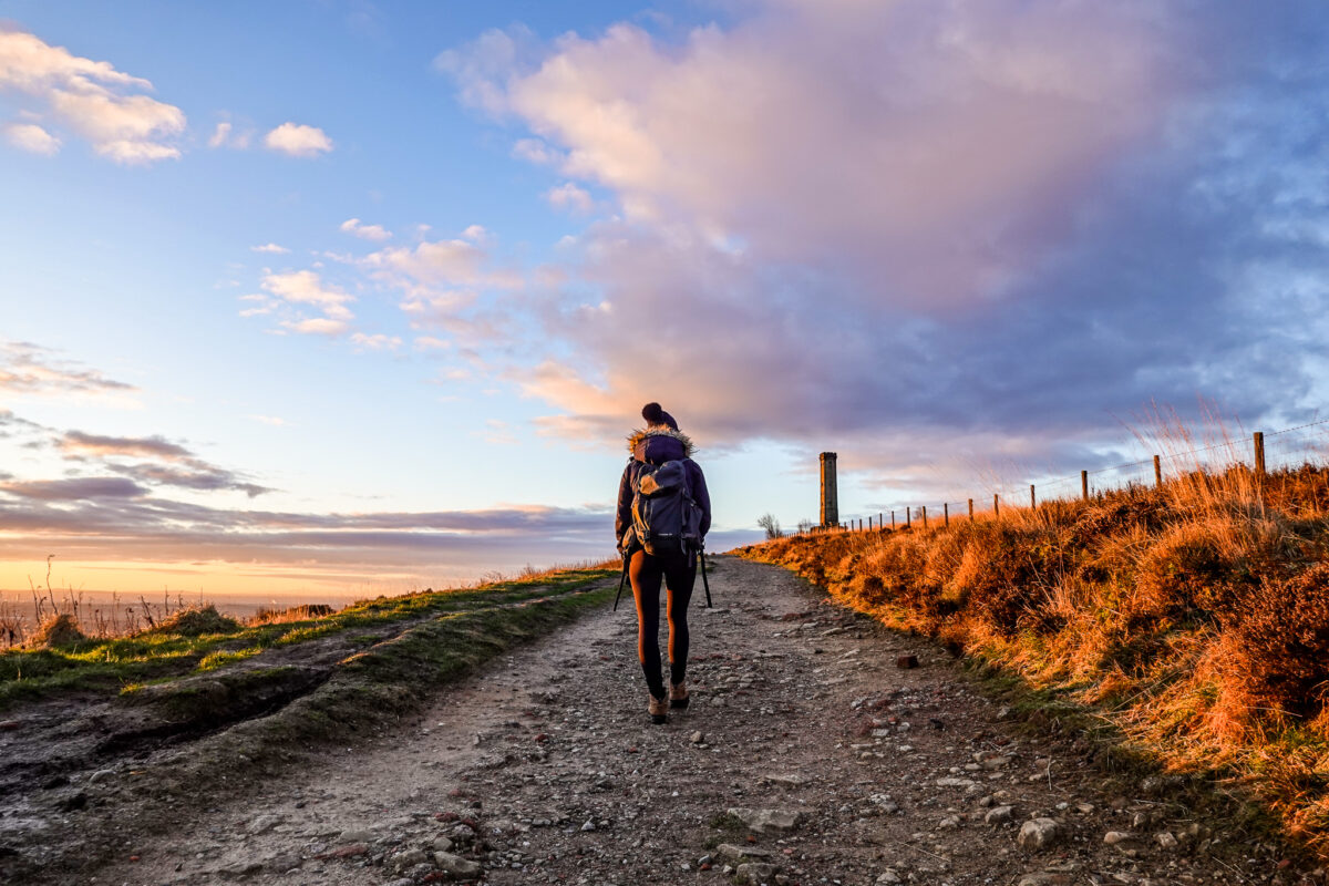 Girl hikes along path up hill in countryside