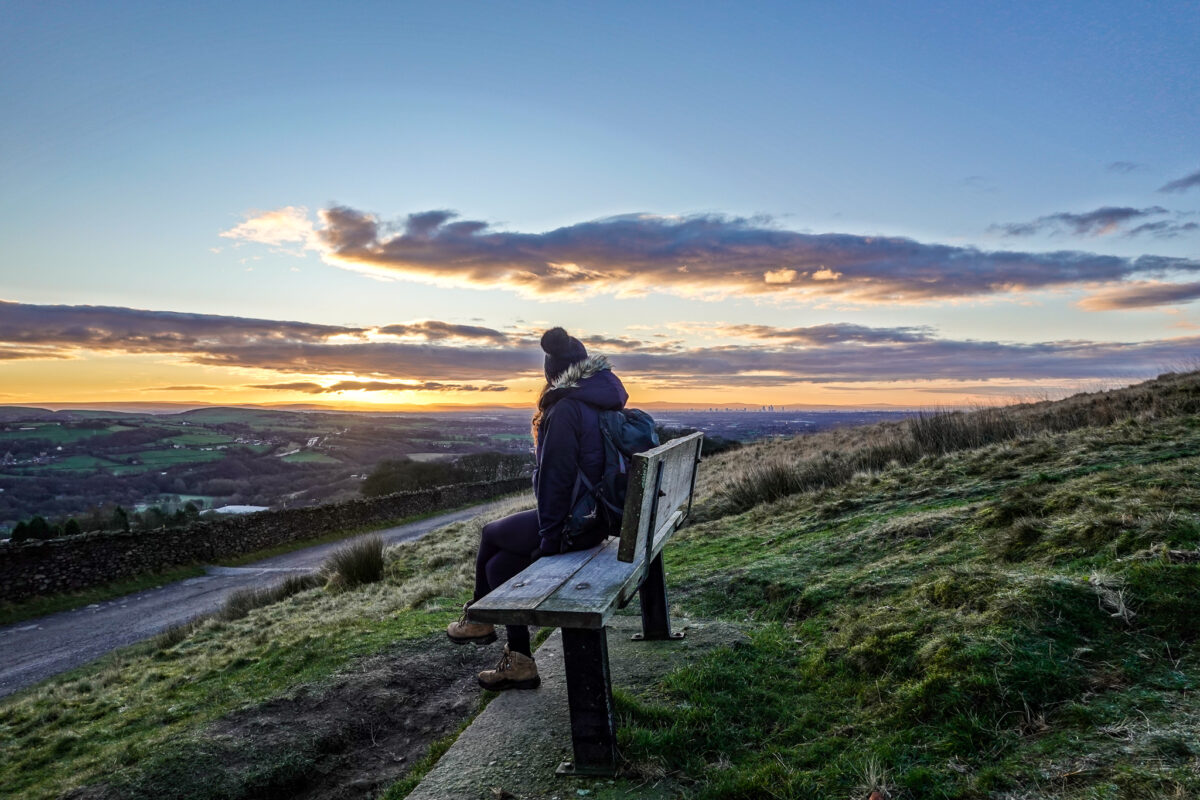 Girl sitting on bench looking over city.