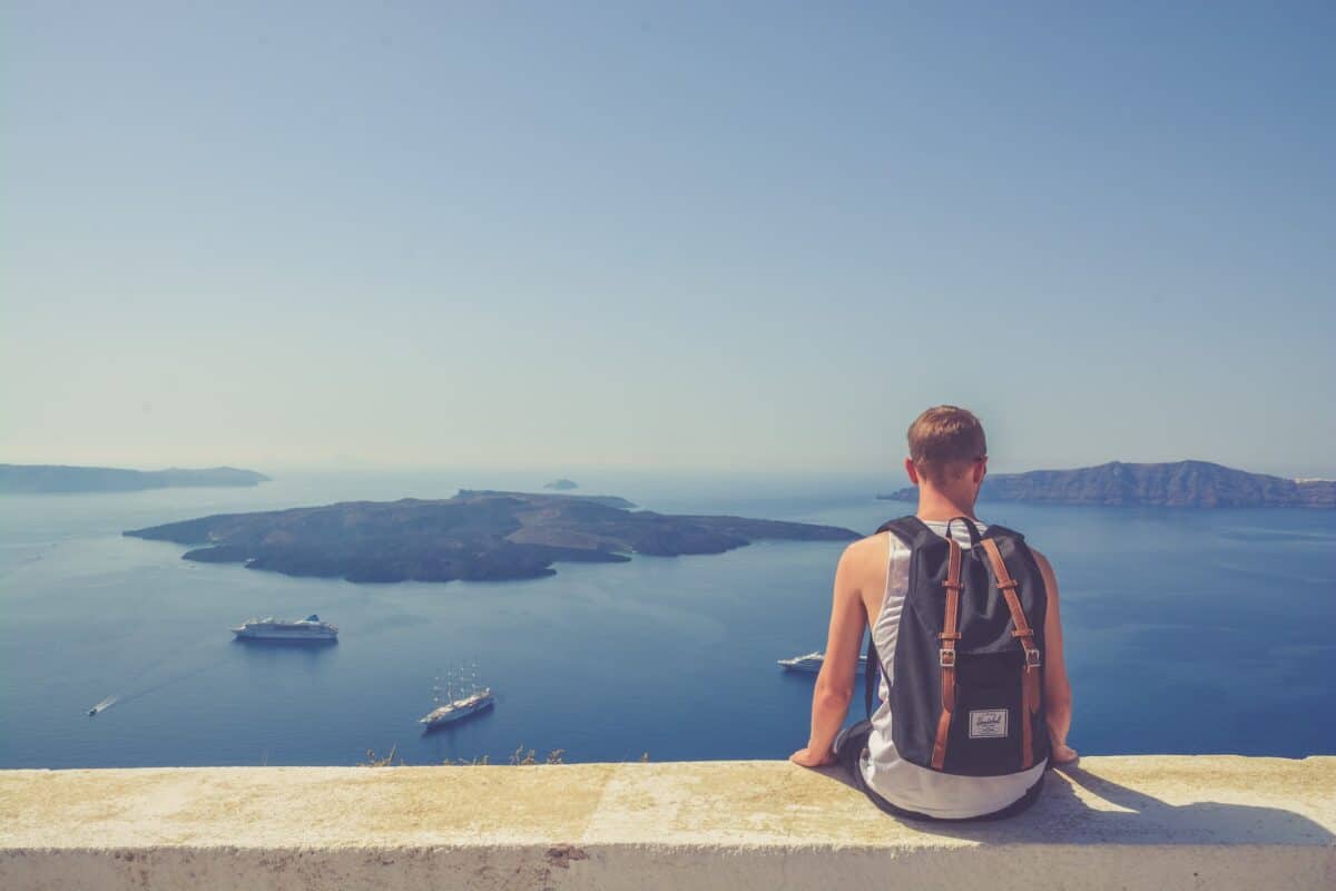 Man wears backpack in Greece over looking the sea and islands